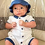 baby, infant, child, hat, bucket_hat, white_clothing, navy_clothing, buttoned_onesie, sitting, chair, beige_background, cute, portrait, young_child, indoor, skin, face, hands, legs, expression