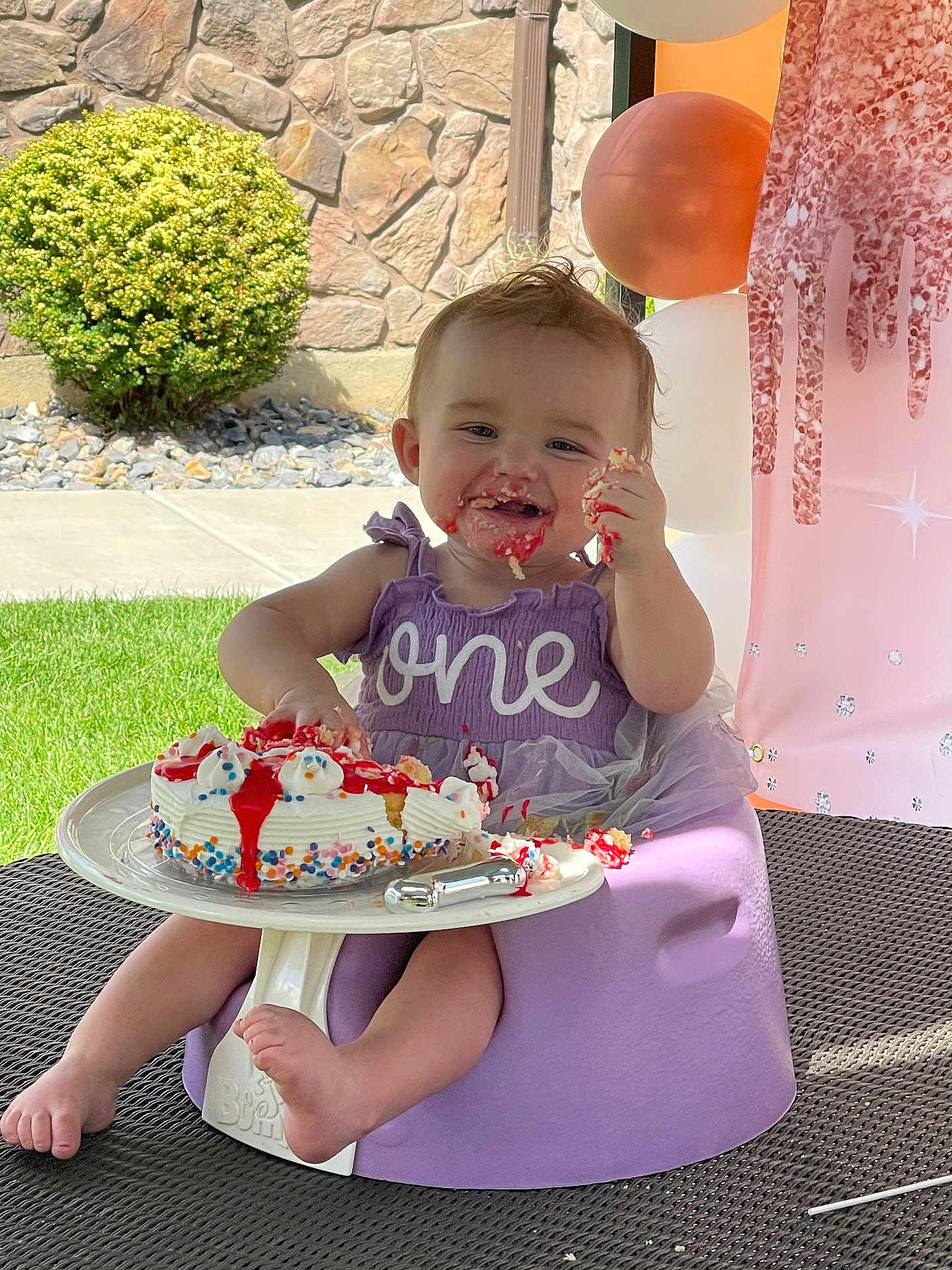 Ayrora joined the competition — help win amazing prizes! baby, birthday_cake, purple_dress, smiling, face, hand, frosting, sprinkles, outdoor, grass, balloons, decorations, seat, foot, table, celebration, one_year_old, happy, messy, child