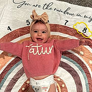 Tatum joined the competition — help win amazing prizes! baby, blanket, carpet, child, clothing, cute, diaper, happy, headband, headwear, indoor, infant, numbers, person, pink_sweater, playful, portrait, rainbow, smiling, toddler