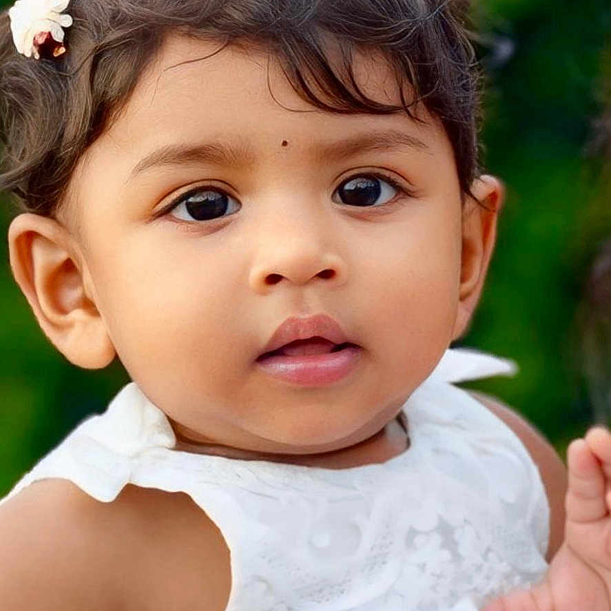 Ophelia Enza is registered to the contest to win money with this photo: baby, child, close_up, curly_hair, cute, eyes, face, flower, hair_accessory, infant, innocent, nature_background, outdoor, person, portrait, skin, soft_lighting, summer, white_dress, young_child