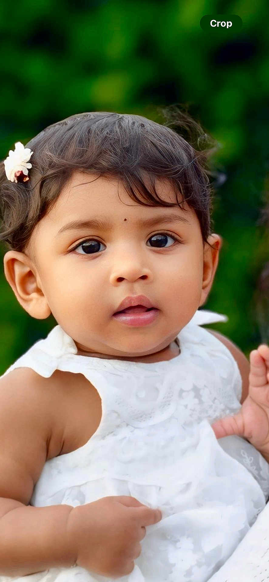 Ophelia Enza is registered to the contest to win money with this photo: baby, child, portrait, close_up, white_dress, flower, hair_accessory, curly_hair, cute, innocent, skin, face, eyes, outdoor, nature_background, young_child, person, infant, soft_lighting, summer