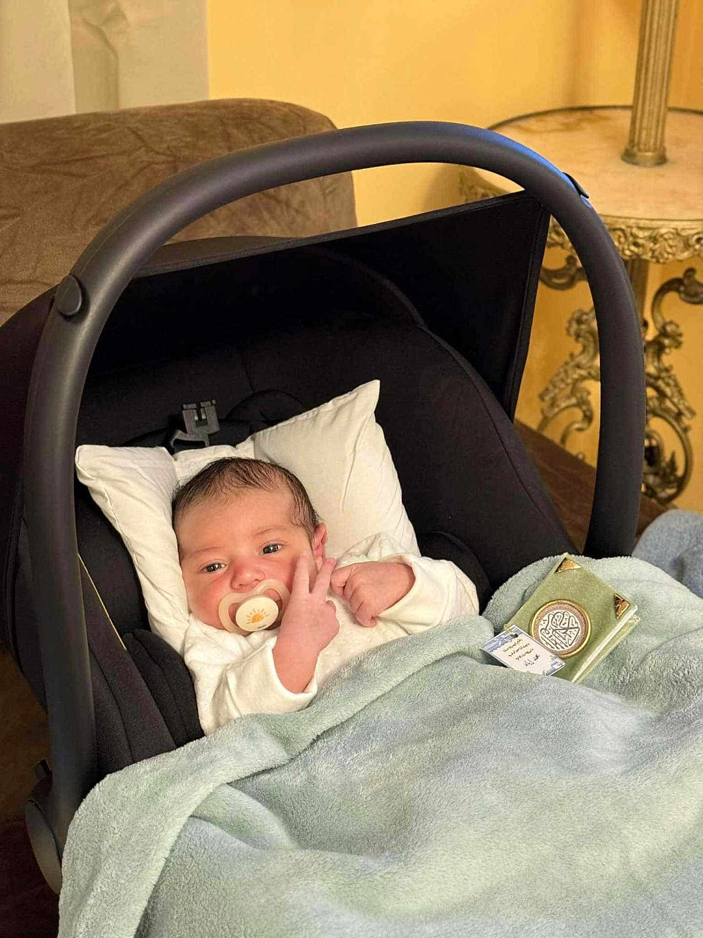 Mohmed Iyed participe au concours pour gagner de l'argent avec cette photo : baby, baby_carrier, blanket, clothing, comfort, couch, cute, face, furniture, hand, indoor, infant, newborn, pacifier, person, pillow, resting, soft, table, warm