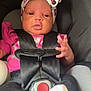 baby, infant, car_seat, headband, pink_clothing, black_straps, safety_harness, cute, small_hands, white_socks, black_pants, child, seatbelt, adorable, young, portrait, indoor, person, newborn, closeup