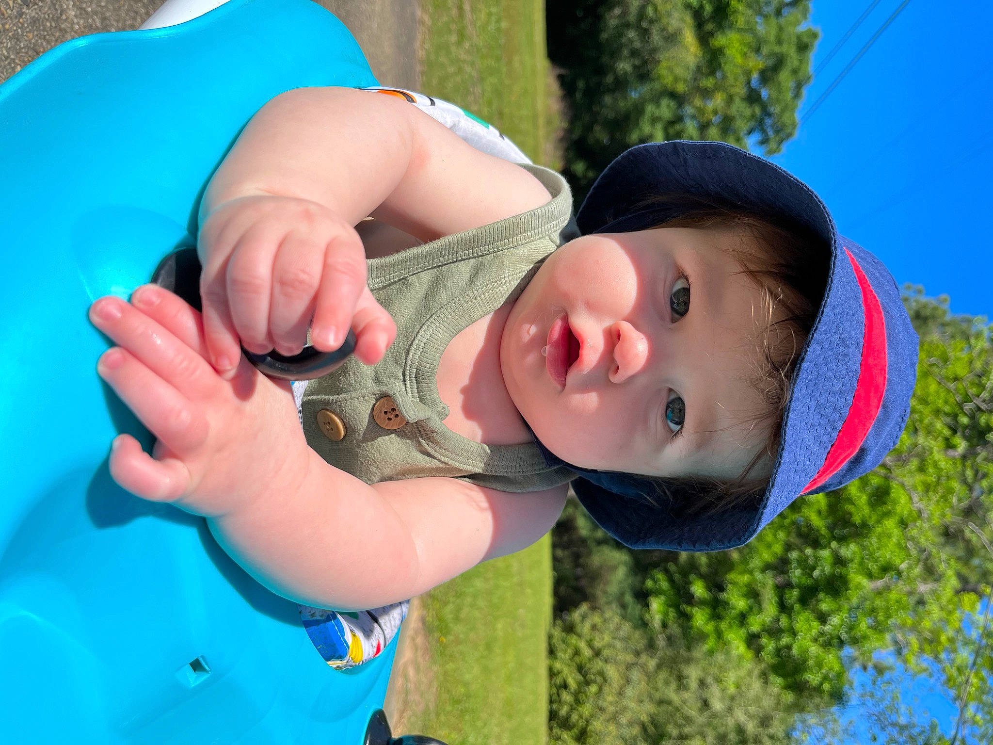 Corbin is registered to the contest to win money with this photo: blue, child, electric_blue, fun, gesture, grass, green, happy, hat, headwear, leisure, mouth, nail, people_in_nature, person, plant, recreation, sky, thumb, toddler