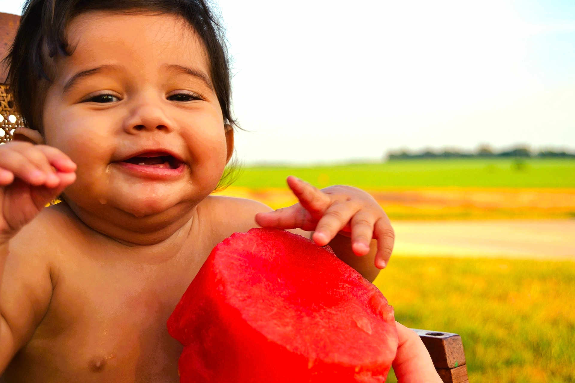 River is registered to the contest to win money with this photo: baby, child, watermelon, fruit, smiling, happy, outdoor, nature, summer, greenery, hand, skin, food, fresh, cute, portrait, closeup, grass, sunlight, joy