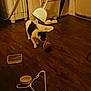 cat, black_and_white_cat, hardwood_floor, dustpan, towel, yarn_ball, plastic_container, hanger, bowls, door, wall, corner, indoor, low_light, clutter, pet, curiosity, floor_texture, household_item, playtime