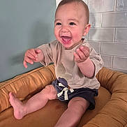 Achille a rejoint le concours — aidez-le/la à gagner de superbes lots ! baby, child, smiling, happy, sitting, cushion, seat, indoor, clothing, shorts, tshirt, face, hands, legs, foot, head, baby_furniture, tile_wall, light, expression
