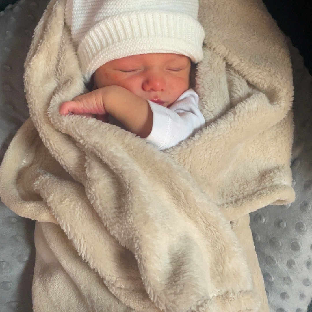 Nino participe au concours pour gagner de l'argent avec cette photo : arm, baby, beige_blanket, blanket, cozy, cushion, face, hand, indoors, infant, knit_hat, newborn, nursery, peaceful, portrait, seat, sleeping, soft_texture, swaddle, white_hat