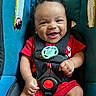 baby, infant, child, smiling, happy, portrait, car_seat, safety_harness, pacifier, red_clothing, seated, indoor, close_up, face, eyes, hands, legs, automotive, travel, safety