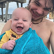 Esmae joined the competition — help win amazing prizes! baby, infant, adult, smiling, happy, portrait, beach, outdoor, towel, turquoise, yellow_clothing, wet_hair, bare_shoulders, bridge, concrete, architecture, waterfront, closeup, family, sunny_day
