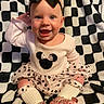 baby, child, infant, smiling, happy, portrait, bow, hair_accessory, dress, tutu, polka_dot, shirt, socks, shoes, heart_pattern, seated, blanket, black_and_white, indoors, fashion