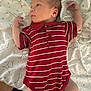 Jaxten is registered to the contest to win money with this photo: baby, infant, clothing, red_onesie, striped_clothing, blanket, star_pattern, white_socks, lying_down, curious, newborn, person, cute, small_hands, soft_lighting, indoor, portrait, young_child, skin, face