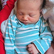 Jaxten joined the competition — help win amazing prizes! baby, newborn, sleeping, striped_clothing, pajamas, hand, red_sweater, blanket, person, footwear, socks, hello_kitty, indoor, closeup, infant, peaceful, cute, soft_light, portrait, cozy