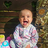 Emma joined the competition — help win amazing prizes! baby, child, smile, laughing, pajamas, bench, wood, heart_shaped_cutout, plush_toy, cushion, floral_pattern, outdoor, sunlight, happy, person, cute, sitting, infant, portrait, colorful