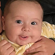 Theodore joined the competition — help win amazing prizes! baby, close_up, face, smile, eyes, hands, blanket, yellow, cozy, infant, cute, child, skin, expression, portrait, adorable, young, indoor, warm, happy