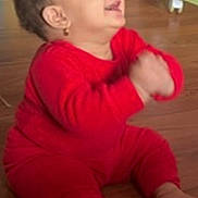 Renad is registered to the contest to win money with this photo: baby, child, red_clothing, sitting, clapping, happy, indoor, floor, wooden_floor, hand, thumbs_up, person, toddler, cute, smile, long_sleeve, foot, infant, playful, young_child