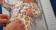 Athena is registered to the contest to win money with this photo: baby, infant, onesie, animal_print, changing_pad, hands, care, cute, colorful, pattern, child, newborn, clothing, fabric, person, skin, indoor, blue_background, parent, snap_buttons