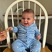 Scarlett joined the competition — help win amazing prizes! baby, child, blue_clothing, onesie, chair, wooden_chair, hand, finger, smiling, happy, indoor, furniture, dining_room, table, person, infant, seated, cute, face, expression