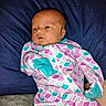 baby, infant, pajamas, onesie, colorful_clothing, lying_down, blue_pillow, blanket, face, head, newborn, indoors, sleepwear, person, cute, soft_texture, relaxed, skin, child, resting