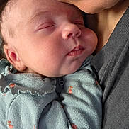 Zoey is registered to the contest to win money with this photo: newborn, baby, sleeping, infant, face, portrait, close_up, cuddling, parent, adult, peaceful, eyes_closed, cheeks, nose, mouth, clothing, onesie, floral_pattern, holding, indoor