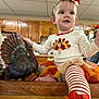 Kinsley joined the competition — help win amazing prizes! toddler, child, indoor, kitchen, turkey, decorative_turkey, headband, striped_leggings, orange, white, festive_clothing, holiday, smiling, sitting, wooden_surface, cabinet, cute, baby, person, celebration