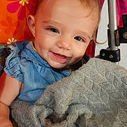 Lou joined the competition — help win amazing prizes! baby, child, smiling, blanket, blue_clothing, floral_background, happy, indoor, person, portrait, cute, toddler, hand, face, fabric, colorful, seat, comfort, expression, soft