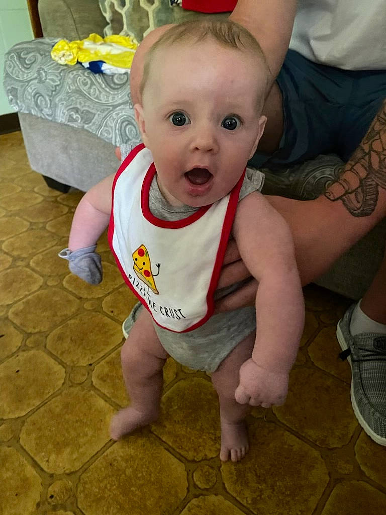 Owen is registered to the contest to win money with this photo: baby, baby_toddler_clothing, beauty, cheek, child, eye, face, floor, flooring, foot, happy, head, iris, leg, mouth, person, skin, sleeve, smile, surprise