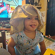 River is registered to the contest to win money with this photo: toddler, child, blanket, tongue_out, indoor, living_room, television, cartoon, furniture, toy, smiling, shirt, person, home, candid, cute, playful, colorful, young_child, casual