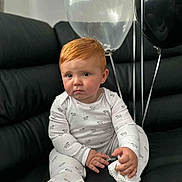 Henry joined the competition — help win amazing prizes! baby, child, red_hair, pajamas, sheep_pattern, black_couch, balloons, white_balloon, black_balloon, indoor, sitting, footwear, cozy, cute, infant, portrait, one_person, expression, hand, looking