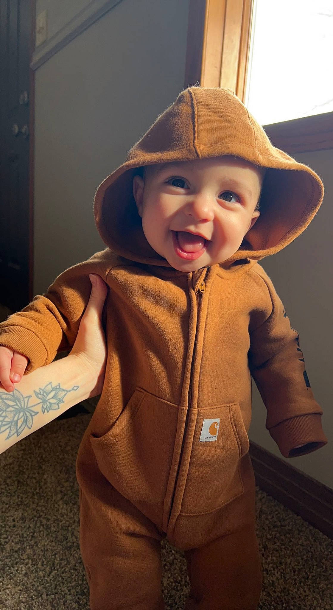 Bentley is registered to the contest to win money with this photo: baby_toddler_clothing, cap, cheek, face, flooring, happy, hat, head, headwear, human_body, jacket, lip, mouth, neck, nose, outerwear, person, shoulder, skin, sleeve