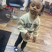 Remi is registered to the contest to win money with this photo: child, braids, beads, sweatshirt, california, west_coast, sneakers, black_and_white, pants, standing, salon_chair, wooden_floor, indoor, person, hairstyle, casual_clothing, young, people, room, fashion