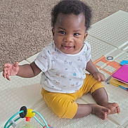 Adesewa joined the competition — help win amazing prizes! baby, child, smiling, sitting, indoors, toy, play_mat, white_shirt, yellow_pants, happy, infant, cute, carpet, playtime, colorful_toy, person, portrait, young_child, hand, feet