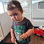 Crixus is registered to the contest to win money with this photo: toddler, child, baby_yoda, tshirt, kitchen, toy, fire_truck, floor, cabinet, stove, snack, curly_hair, barefoot, standing, indoor, expression, person, young_child, cute, casual_clothing