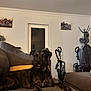 dog, brindle, couch, living_room, vacuum_cleaner, coat_rack, hat, jacket, wall_art, door, furniture, indoor, pet, animal, floor, relaxing, home, car_picture, brown, curious