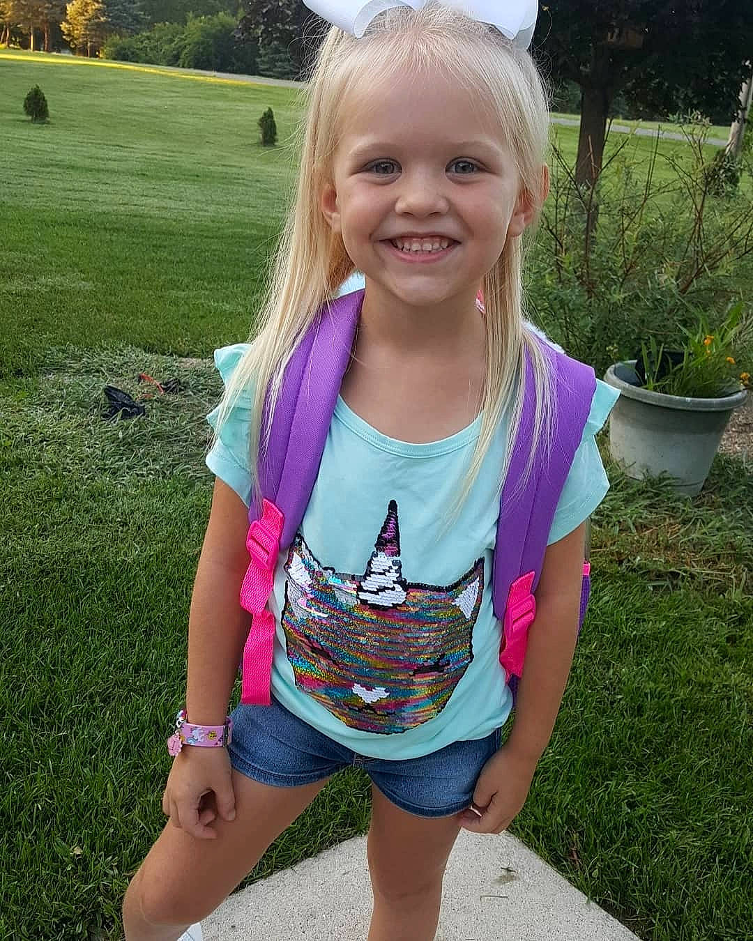 Mollie is registered to the contest to win money with this photo: baby_toddler_clothing, cool, facial_expression, flowerpot, grass, hair, happy, head, iris, joy, leisure, neck, people_in_nature, person, pink, plant, skin, sleeve, smile, standing