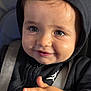 child, baby, toddler, face, eyes, smile, hoodie, black_hoodie, closeup, portrait, car_seat, seatbelt, hand, fingers, cheeks, eyelashes, expression, candid, shallow_depth_of_field, soft_lighting