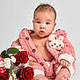 Luna joined the competition — help win amazing prizes! baby, infant, pink_jacket, bunny_patch, flowers, red_roses, white_flowers, greenery, sitting, bare_chest, cute, portrait, studio, soft_lighting, curly_hair, small_feet, expression, child, adorable, fluffy_clothing