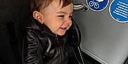 Leyandro a rejoint le concours — aidez-le/la à gagner de superbes lots ! toddler, child, smile, stroller, jacket, jeans, seat_belt, harness, portrait, indoor, public_transport, signage, handrail, hair, face, candid, happy, button, fabric, metal