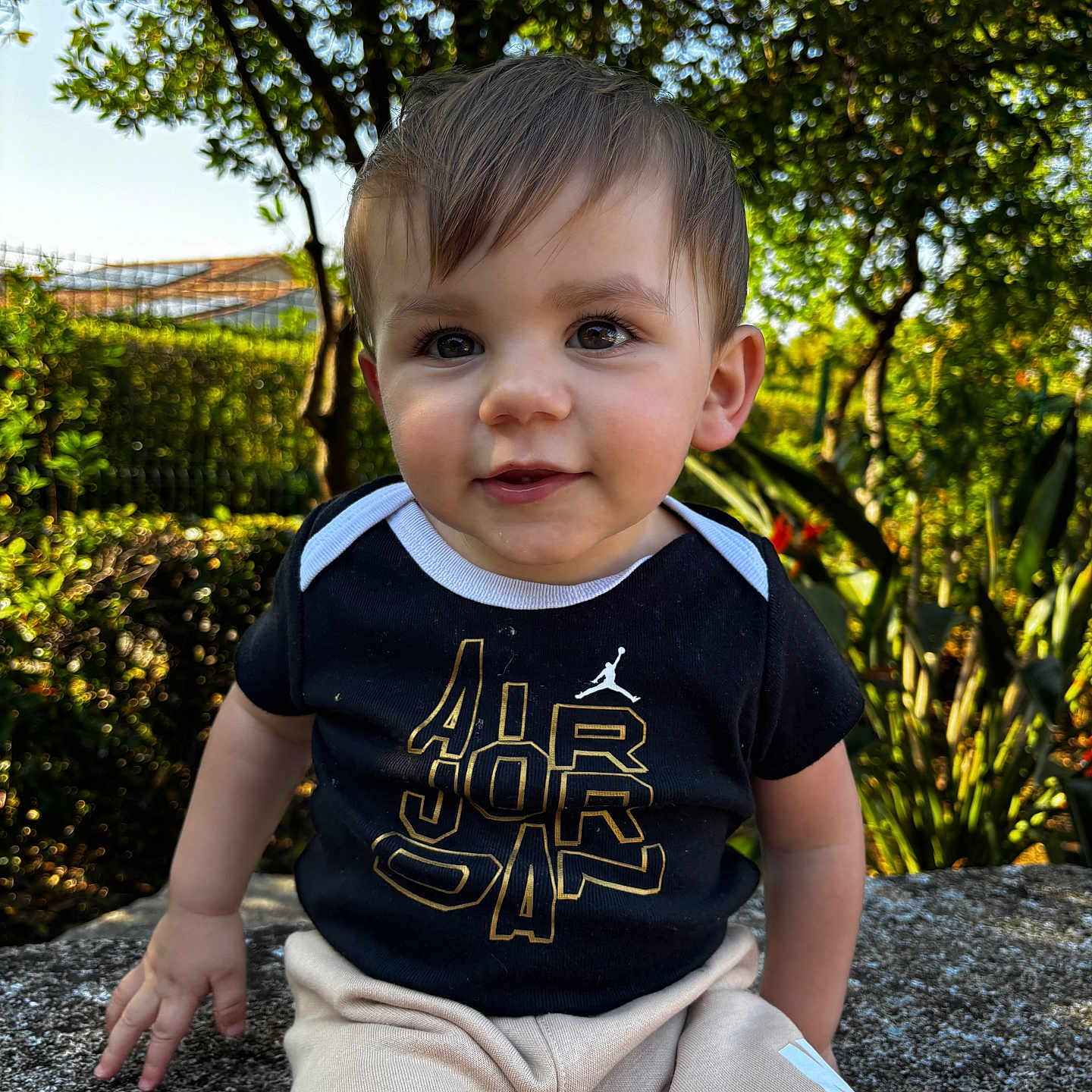 Leyandro participe au concours pour gagner de l'argent avec cette photo : baby, child, cute, daylight, eyes, face, greenery, hair, leaves, outdoor, pants, park, portrait, shirt, sitting, smile, stone_ledge, sunlight, toddler, tree