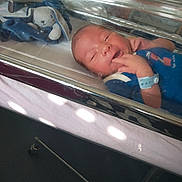 Ismail a rejoint le concours — aidez-le/la à gagner de superbes lots ! newborn, baby, hospital, bassinet, plastic, blue_outfit, wristband, toy, plush_bunny, infant, bed, sleeping, fingers, face, person, healthcare, medical, hospital_room, reflection, cute