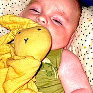 Matys a rejoint le concours — aidez-le/la à gagner de superbes lots ! baby, child, blanket, stuffed_animal, yellow, green_clothing, pillow, sleepy, cuddling, soft_toy, indoor, closeup, face, arm, fabric, pattern, cute, infant, resting, comfort