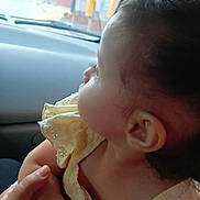Farah is registered to the contest to win money with this photo: baby, child, side_profile, yellow_dress, car_interior, hand, person, curious, infant, skin, ear, face, window, seat, vehicle, portrait, young_child, holding, clothing, close_up