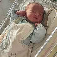 Leo participe au concours pour gagner de l'argent avec cette photo : newborn, baby, sleeping, hospital, bassinet, blanket, infant, cozy, peaceful, face, person, clothing, bed, cute, resting, child, young, indoors, portrait, skin