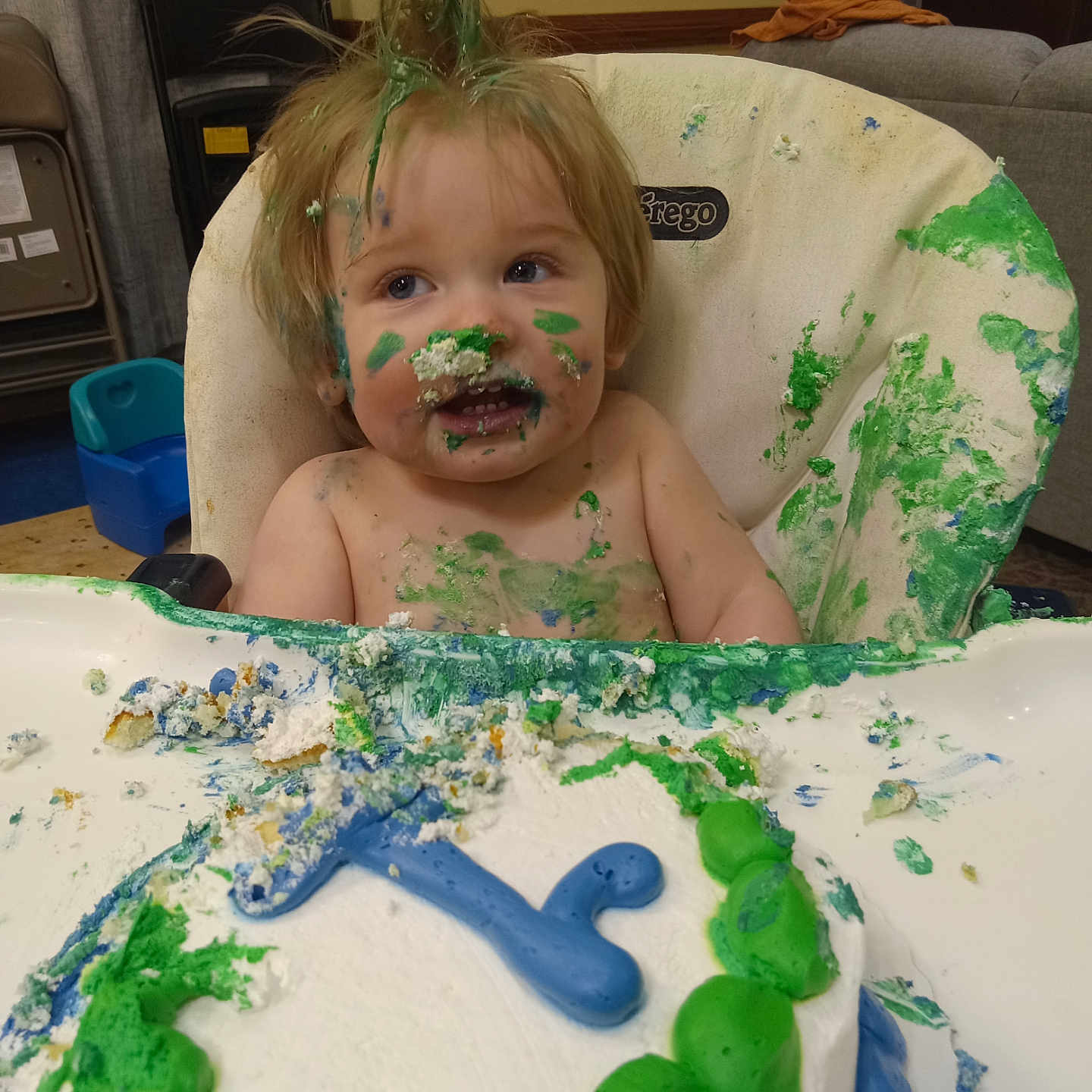 Logan is registered to the contest to win money with this photo: baby, birthdaycake, cake, chair, couch, cream, cupcake, cutlery, dessert, face, food, furniture, head, icecream, icing, person, photography, portrait, spoon, sweets