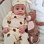 baby, infant, toddler, pajamas, hat, stuffed_animal, teddy_bear, blanket, bed, soft_toy, child, cute, indoors, sleepwear, cozy, lying_down, portrait, face, comfort, calm