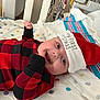 Paisley is registered to the contest to win money with this photo: baby, infant, smiling, santa_hat, christmas, holiday, red_clothing, black_clothing, plaid_pattern, blanket, hospital_bed, newborn, cute, happy, lying_down, face, child, festive, indoors, celebration