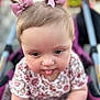 baby, child, toddler, pink_bows, tongue_out, stroller, blue_eyes, close_up, cute, playful, hair_bows, floral_clothing, infant, person, portrait, young_child, soft_focus, outdoor, baby_girl, expression