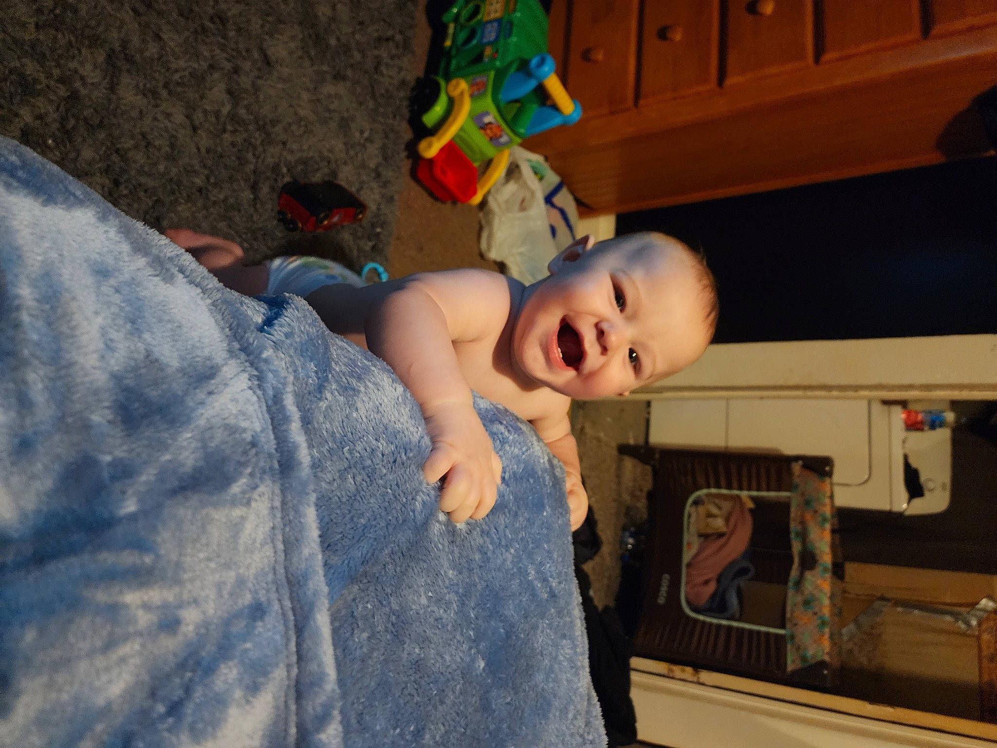 Charlie is registered to the contest to win money with this photo: baby, baby_toddler_clothing, bookcase, cabinetry, chest_of_drawers, child, cupboard, drawer, flooring, fun, home_appliance, person, room, shelf, shelving, sitting, smile, t_shirt, toddler, tree