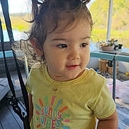 Ellie joined the competition — help win amazing prizes! child, clothing, curious, curly_hair, daylight, diaper, expression, face, furniture, hair, indoor, nature, person, pigtails, porch, standing, sunny_vibes, toddler, window, yellow_tshirt