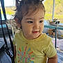 child, clothing, curious, curly_hair, daylight, diaper, expression, face, furniture, hair, indoor, nature, person, pigtails, porch, standing, sunny_vibes, toddler, window, yellow_tshirt